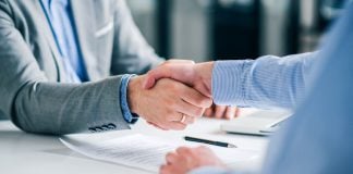 PENN extends retail sportsbook deal with Kambi Two businesspeople shaking hands with a pen and paper on the desk