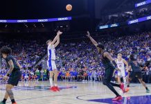 A player shoots over a guard during an NCAA college basketball game
