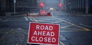 Roadworks on a deserted street with a sign stating "road ahead closed"