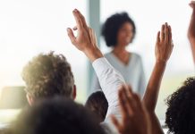 A group of people raise their hands as BetRivers raises its minimum bet amount in Illinois.