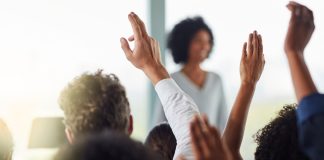 A group of people raise their hands as BetRivers raises its minimum bet amount in Illinois.
