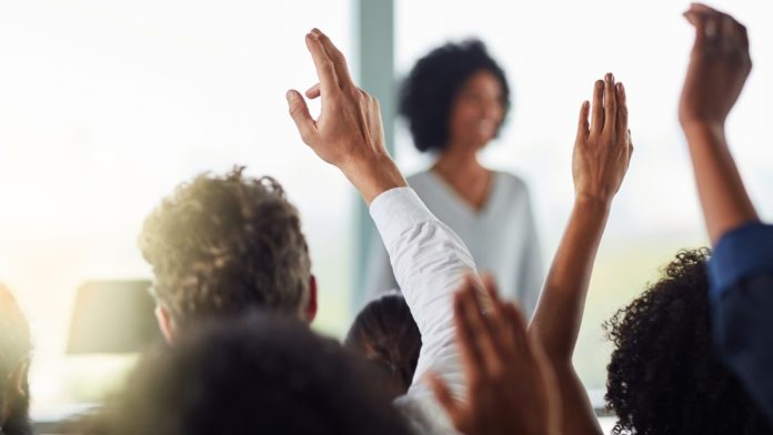 BetRivers-Rush-Street-Interactive-Raises-Bet-Minimum-Illinois A group of people raise their hands as BetRivers raises its minimum bet amount in Illinois.