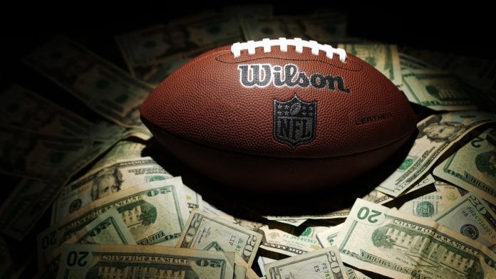 Devin-Booker-Bets-NFLjpg A NFL ball with money as the NBA guard Devin Booker bets on Super Bowl LX.