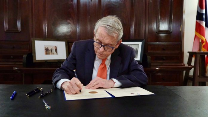 Ohio Gov. Mike DeWine signs a bill as he considers online sports betting his "biggest regret."