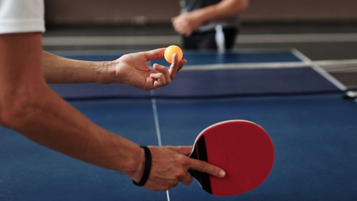 A person preparing to serve in a table tennis game