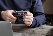 Virginia may consider banning credit cards for sports betting A person sat by a laptop cutting up a credit card