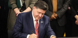 Illinois Gov. JB Pritzker signs a document as he aims to make tax changes for casino gaming.