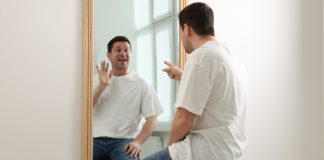 Person looking at themselves in mirror as BetRivers owner RSI considers making changes nationwide that mirror house rules in Illinois.