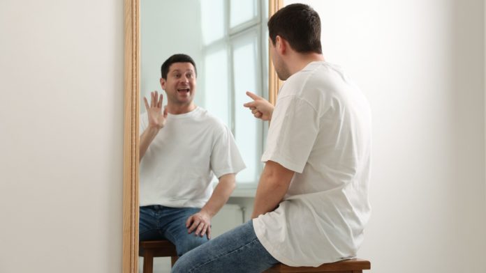 RSI-Bet-Minimum-Rush-Street-Interactive-Earnings-Call-6995e35325021 Person looking at themselves in mirror as BetRivers owner RSI considers making changes nationwide that mirror house rules in Illinois.