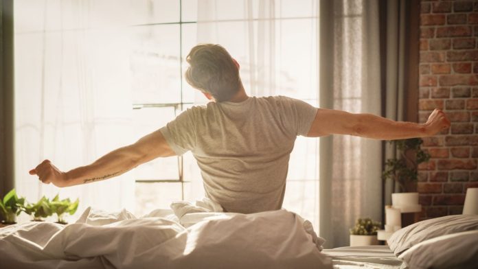 Sleeper-re-awakens-as-prediction-market-through-deal-with-Kalshi A man sits up and stretches in bed after waking up