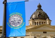 The South Dakota State Capitol building with a state flag in the foreground
