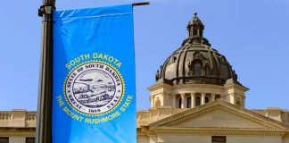 The South Dakota State Capitol building with a state flag in the foreground