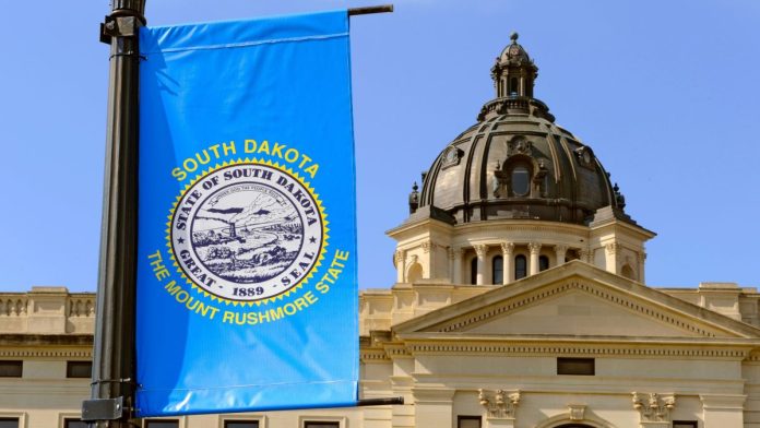 The South Dakota State Capitol building with a state flag in the foreground