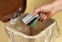 A person throwing credit cards into a trash can
