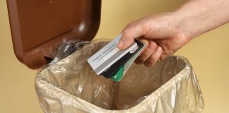 A person throwing credit cards into a trash can