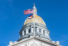 The US and Colorado flags flying on the state capitol building in Denver