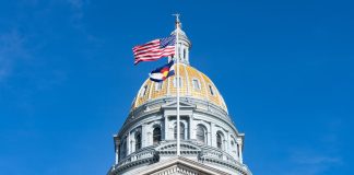 The US and Colorado flags flying on the state capitol building in Denver
