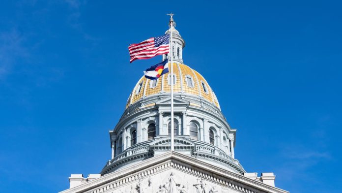 The US and Colorado flags flying on the state capitol building in Denver