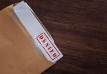 An official document in an envelope with "denied" written on the top