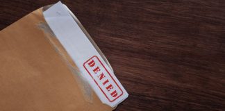 An official document in an envelope with "denied" written on the top