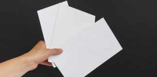 A person holding three white envelopes