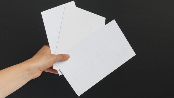 A person holding three white envelopes