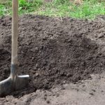 A shovel in the ground digging a hole
