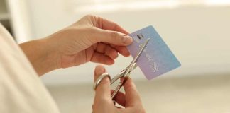 A person cutting a credit card as Ohio considers a regulatory credit card ban.