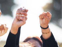 As CFTC outlines sports prediction markets rules, states and tribes take action People with arms raised in protest