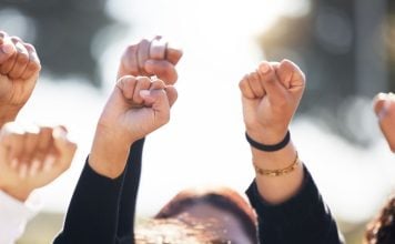 As CFTC outlines sports prediction markets rules, states and tribes take action People with arms raised in protest