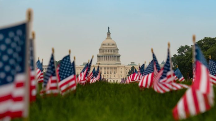 The US Capitol building with US flags in the foreground