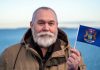 Man holding the state flag of Michigan, where Kalshi faces more court issues