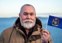 Man holding the state flag of Michigan, where Kalshi faces more court issues