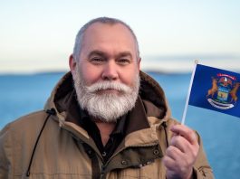 Man holding the state flag of Michigan, where Kalshi faces more court issues