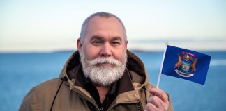 Man holding the state flag of Michigan, where Kalshi faces more court issues