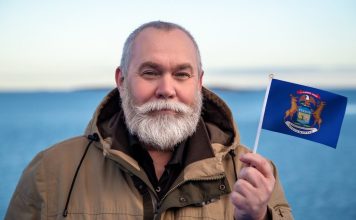 Man holding the state flag of Michigan, where Kalshi faces more court issues