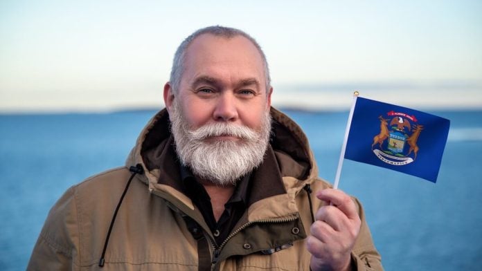 Man holding the state flag of Michigan, where Kalshi faces more court issues